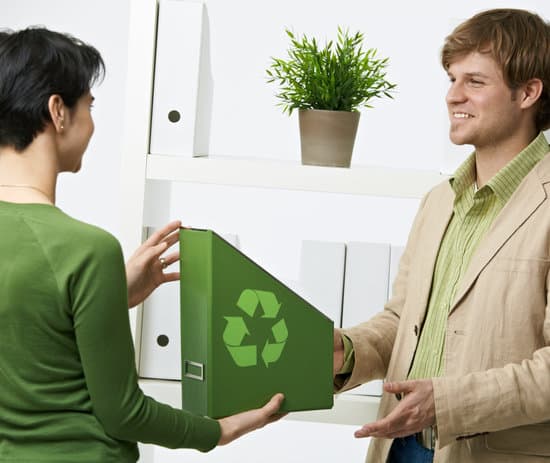 Happy office workers holding green folder with recycling symbol.