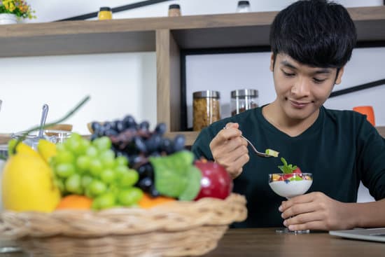 A handsome young Asian man is happy and is eating fruit yoghurt in the modern restaurant. Health care concept