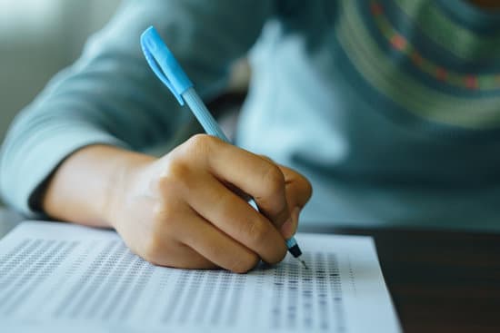 Close up of high school or university student holding a pen writing on answer sheet paper in the examination room. College students answering multiple choice questions test in the testing room in university.