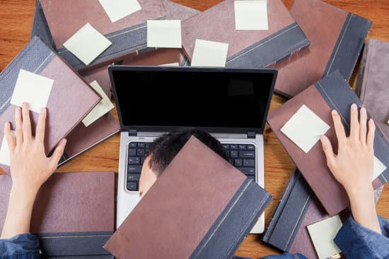 Photo of male college student sleeping above laptop after doing school work with books