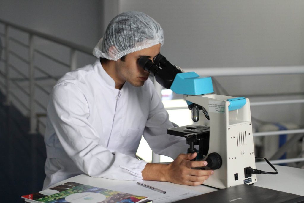A science college student looking on a microscope