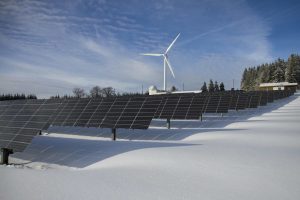 Solar panels and a windmill on a snowy field