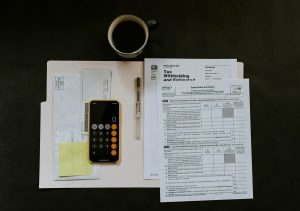Calculator on top of important documents, and a cup of coffee on the table