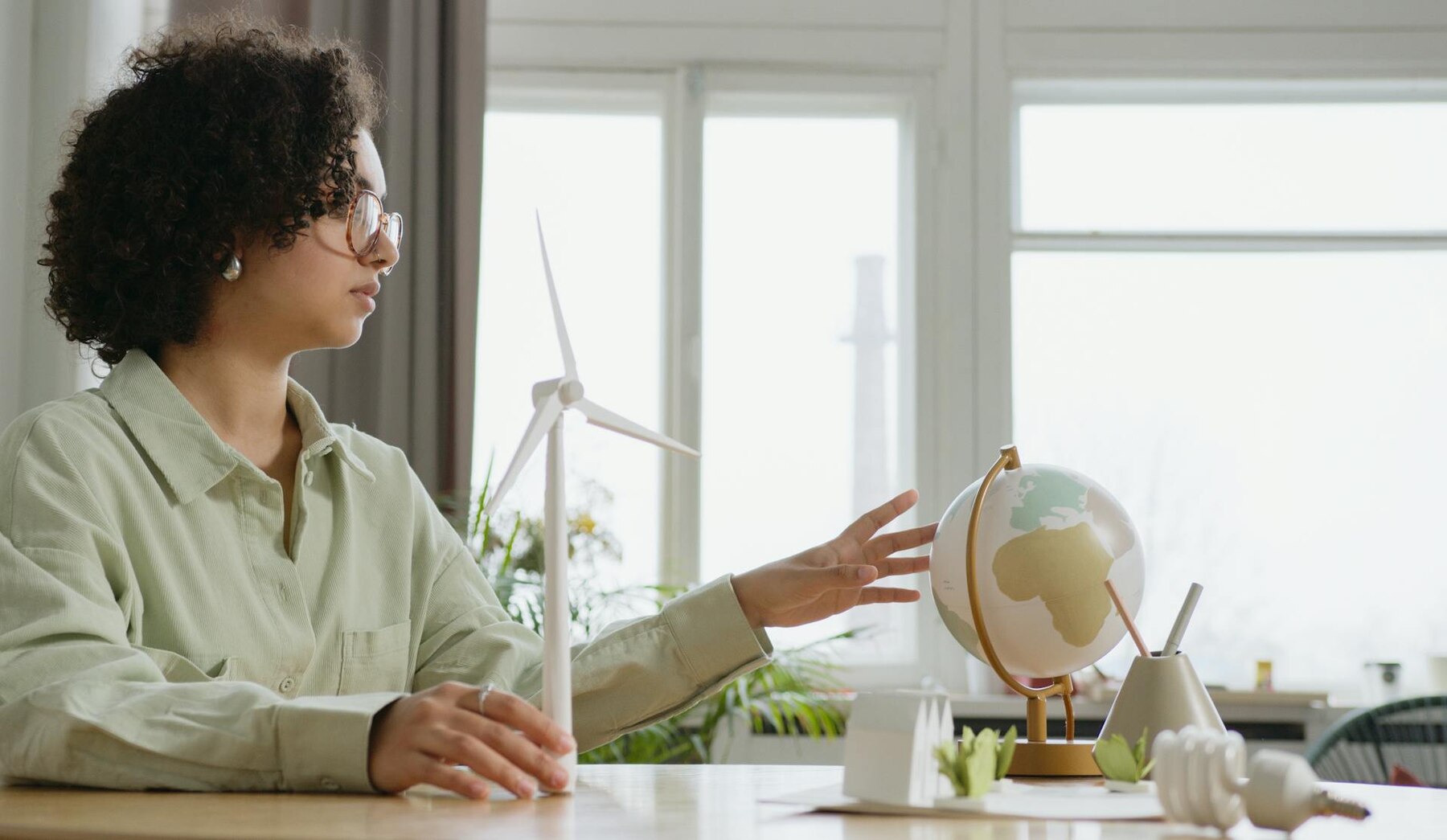 A woman sitting at a table with a globe and wind turbine