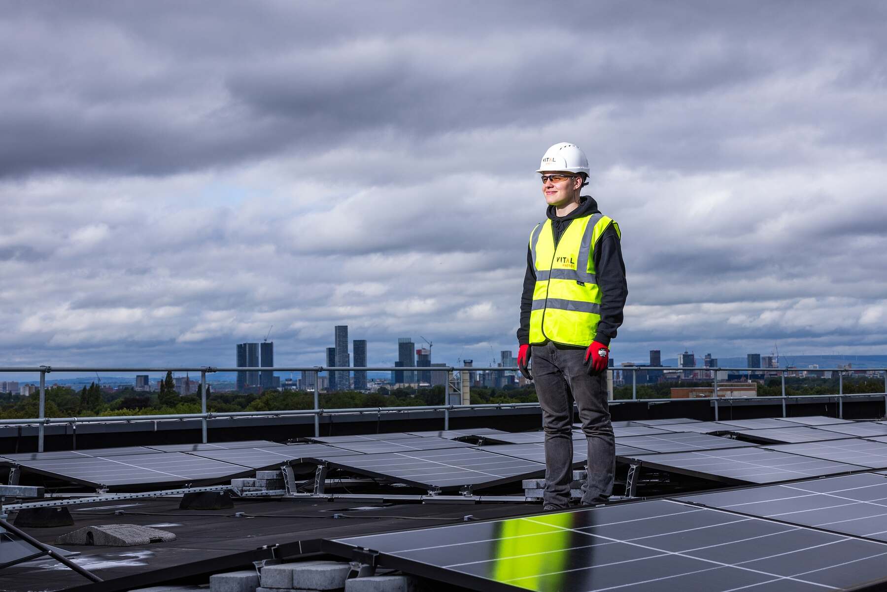 Man wearing protective gear standing on a roof filled with solar panels