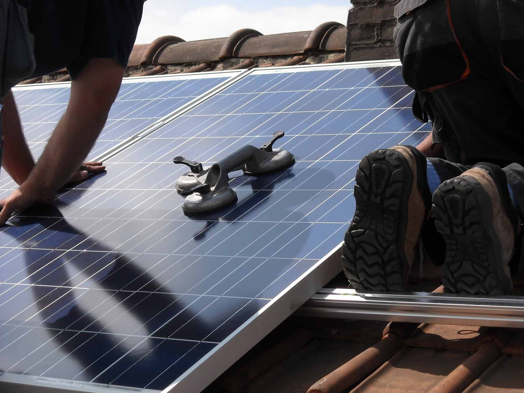 Two men installing solar panels on a house roof