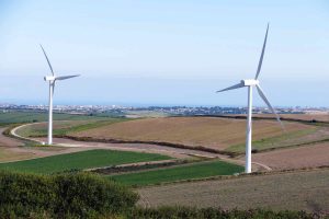 Two wind turbines built on a wide field