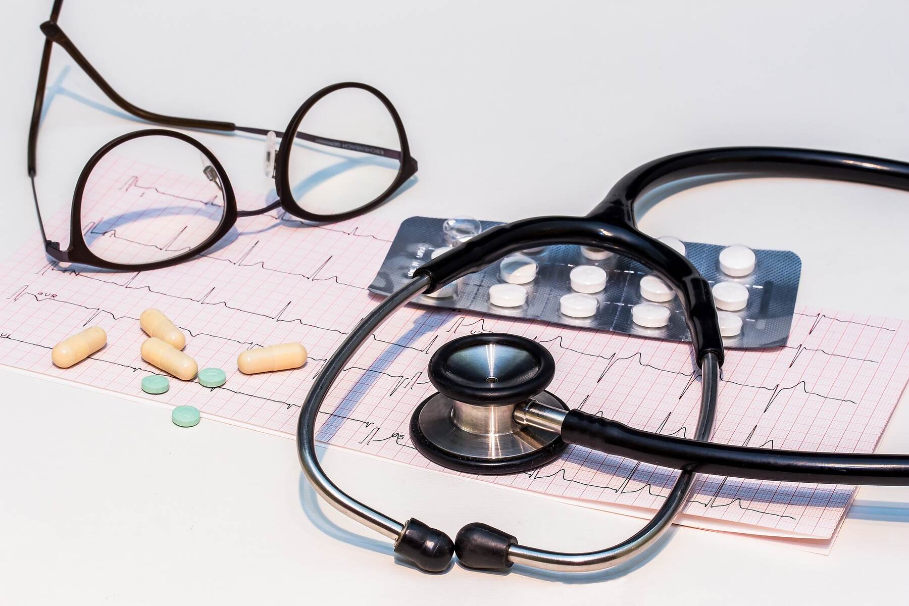 Stethoscope, glasses, and pills on a table