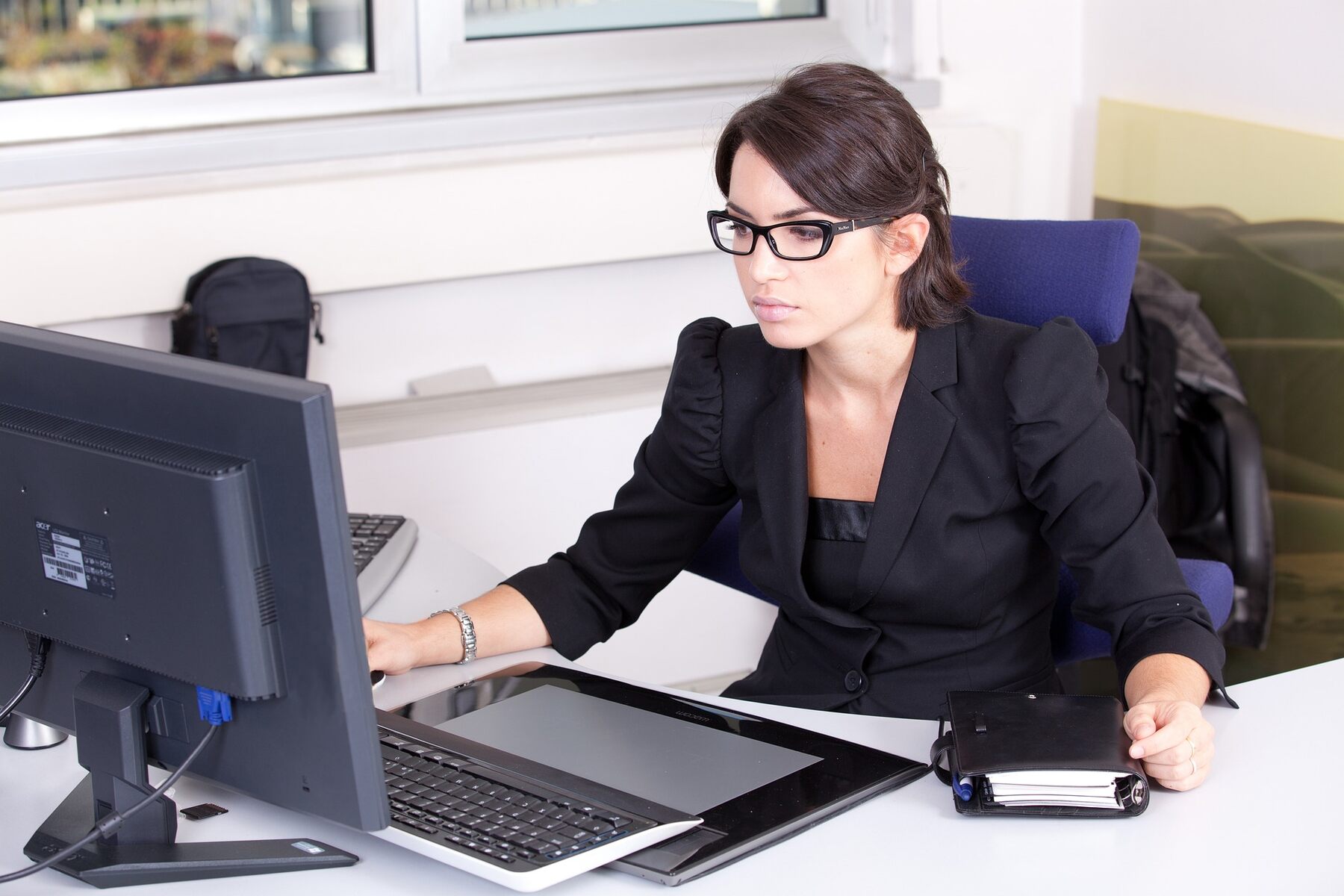 A woman in glasses working on a computer at a desk