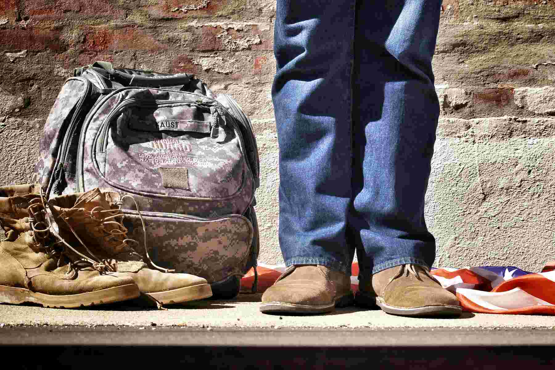 A man standing behind an army bag and shoes