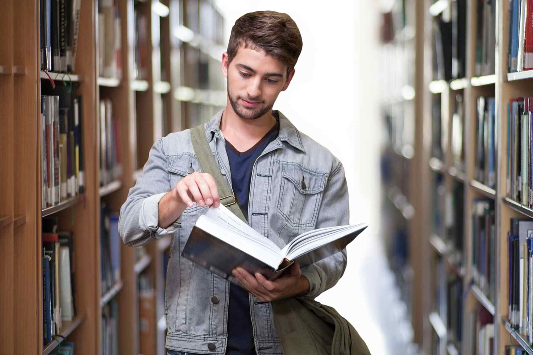 A male student reading a book at a library