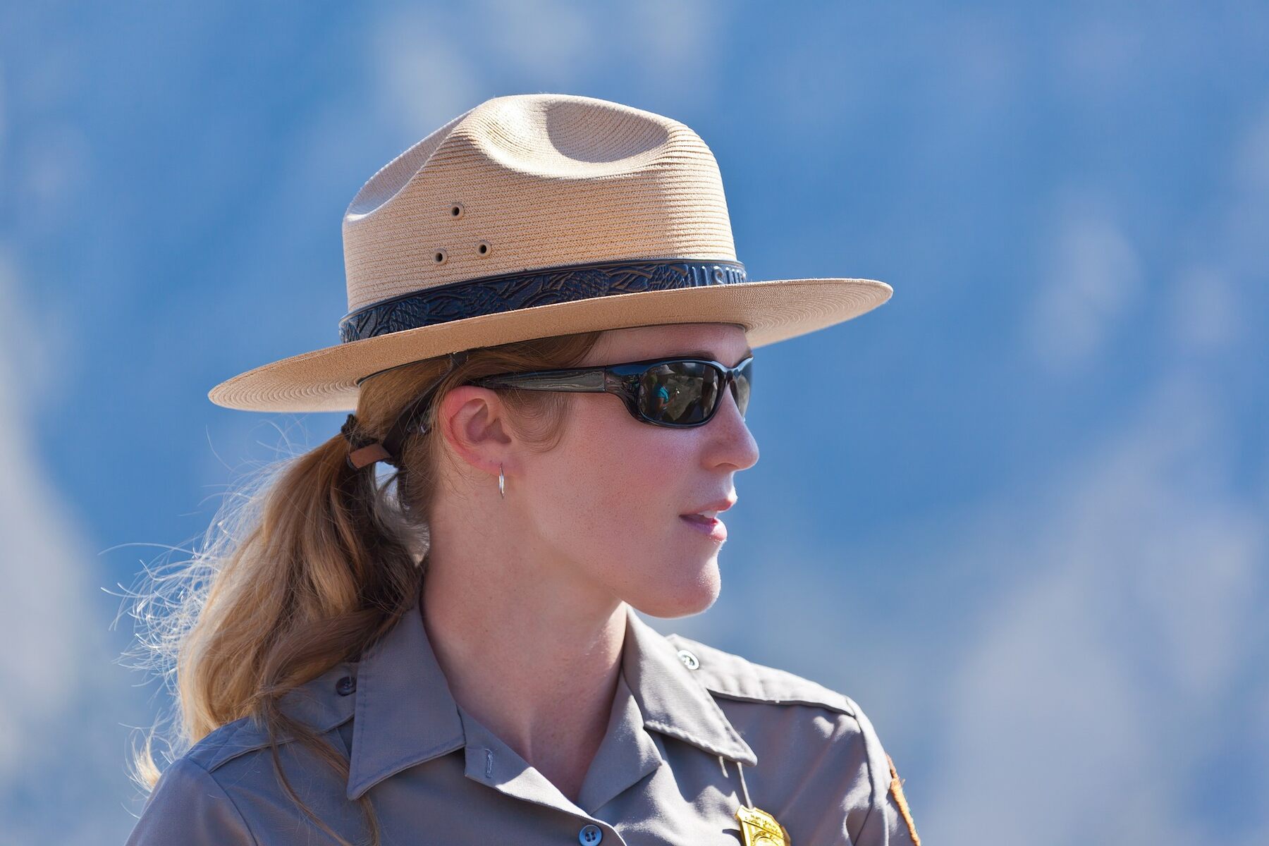 A woman in a hat and sunglasses standing in the desert