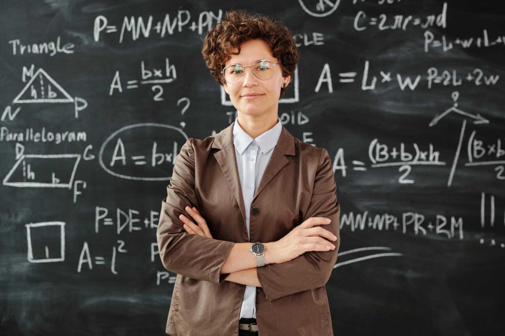 A woman standing with some math equations written on the board behind her
