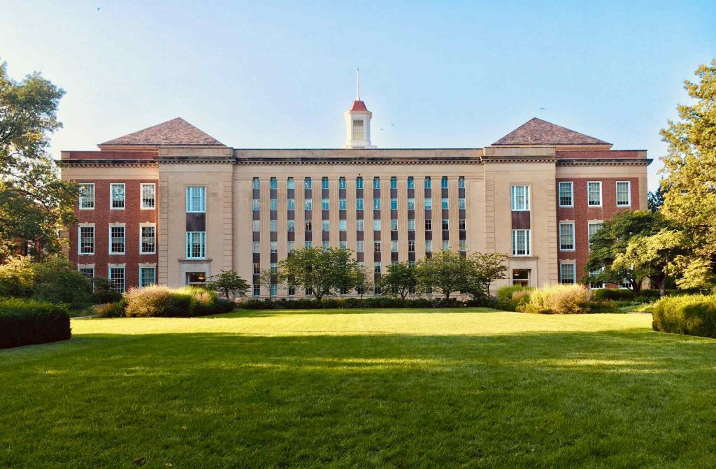 Large building on a college campus with a grassy lawn in front of it
