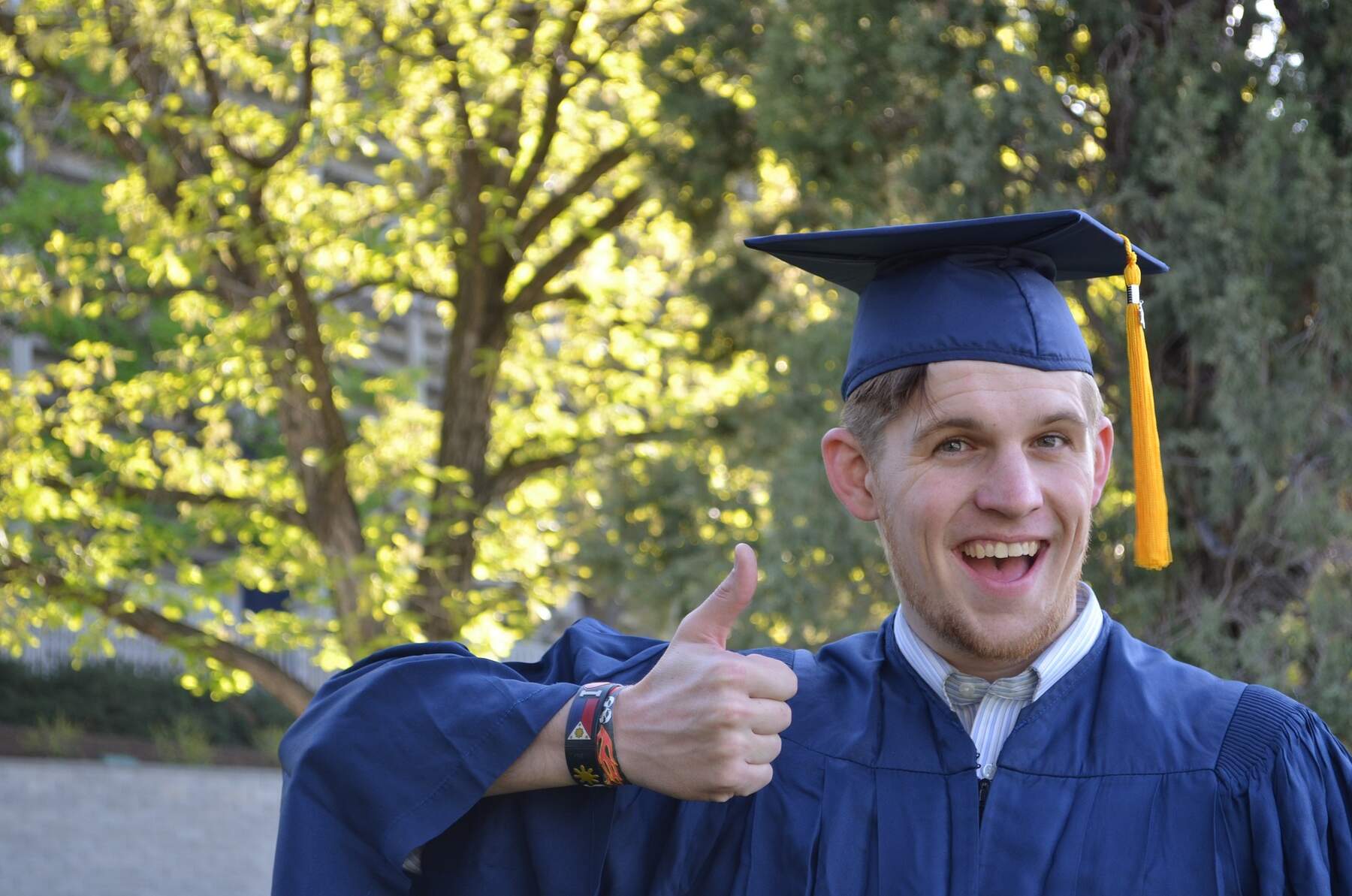 A man in a graduation gown giving a thumbs up
