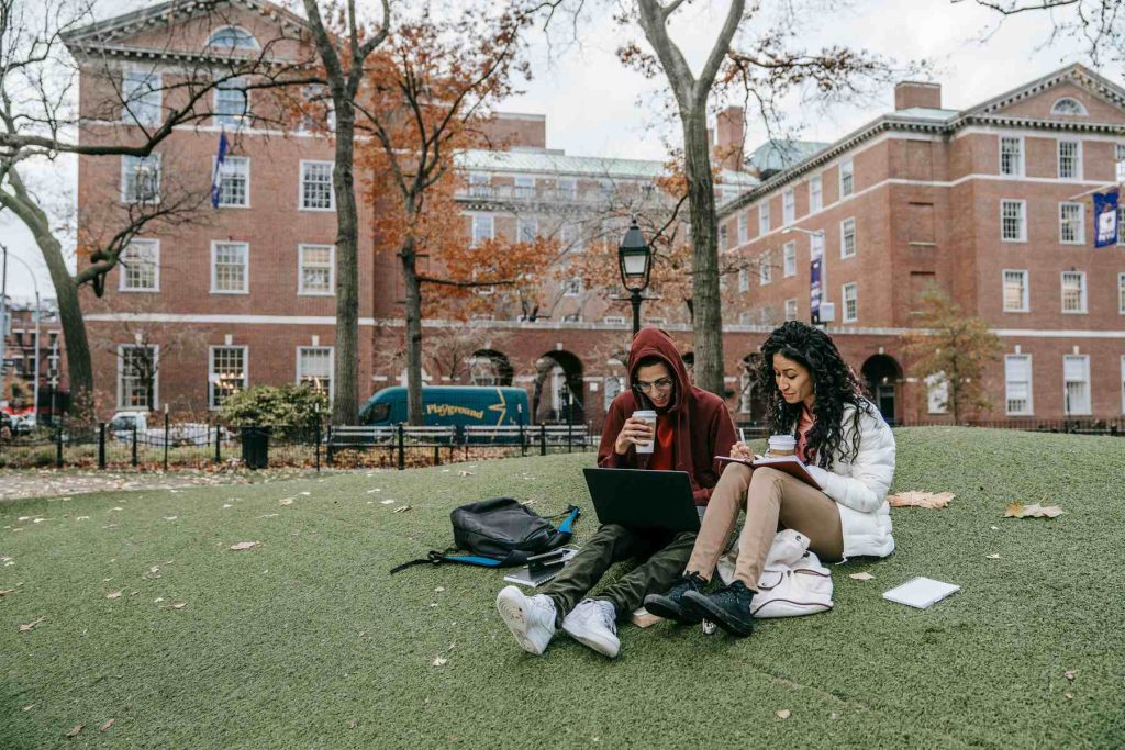 Two students sitting on the grass on a college campus