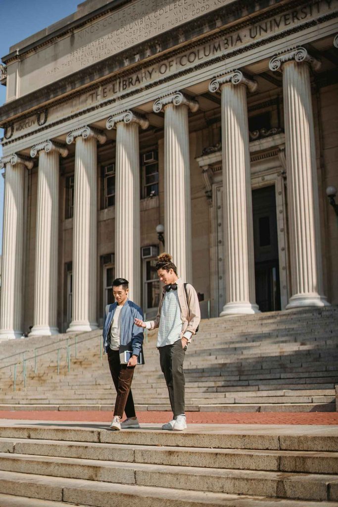 Two college students walking down the stairs outside of a building at Columbia University