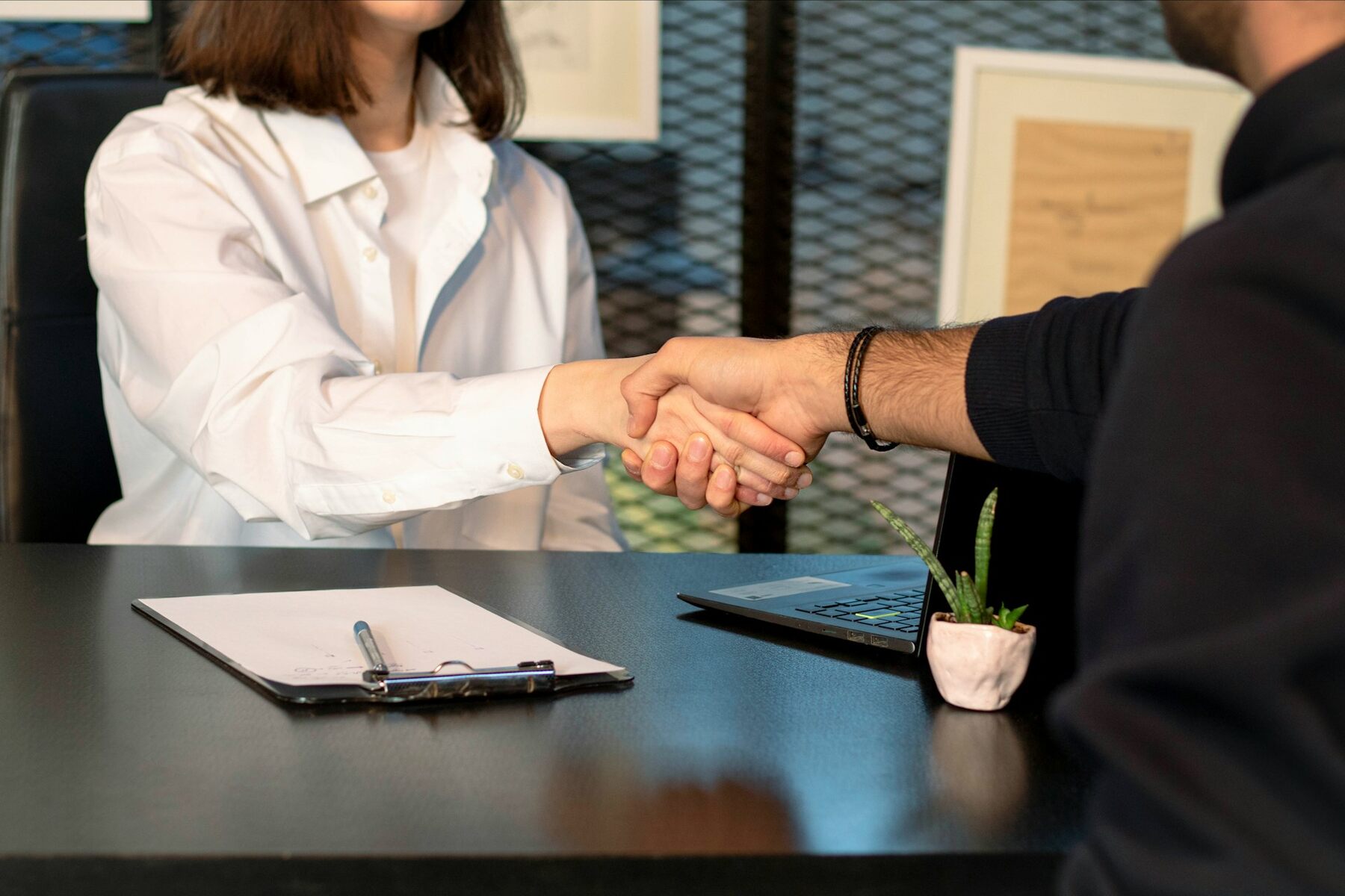 Professional man and woman sealing a deal with a handshake at a desk