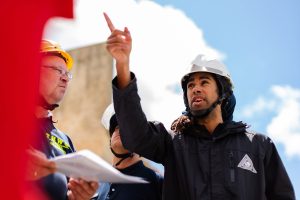 Man wearing protective hat pointing to his team about an outdoor project development