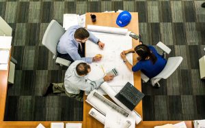 Group of people reviewing a long product diagram laid on the table