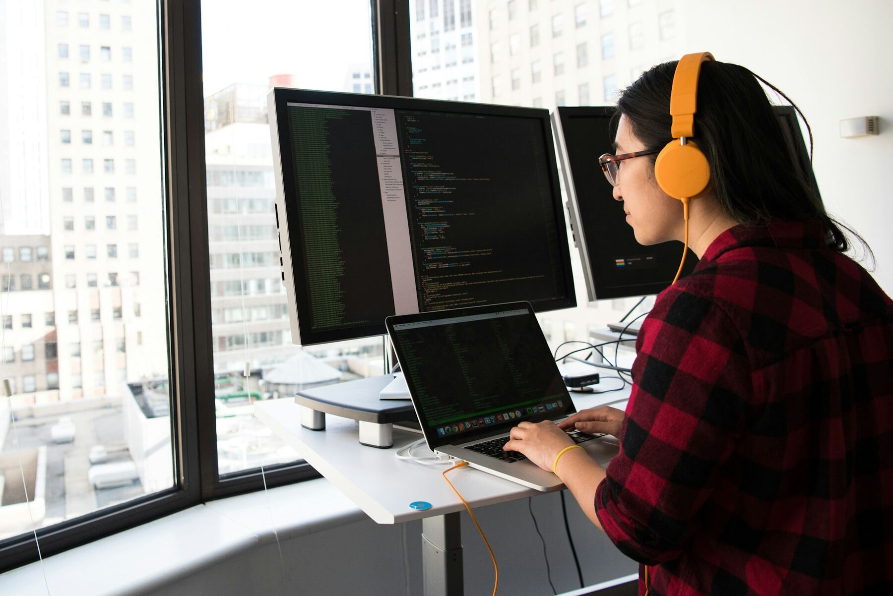 A woman wearing headphones using a laptop computer