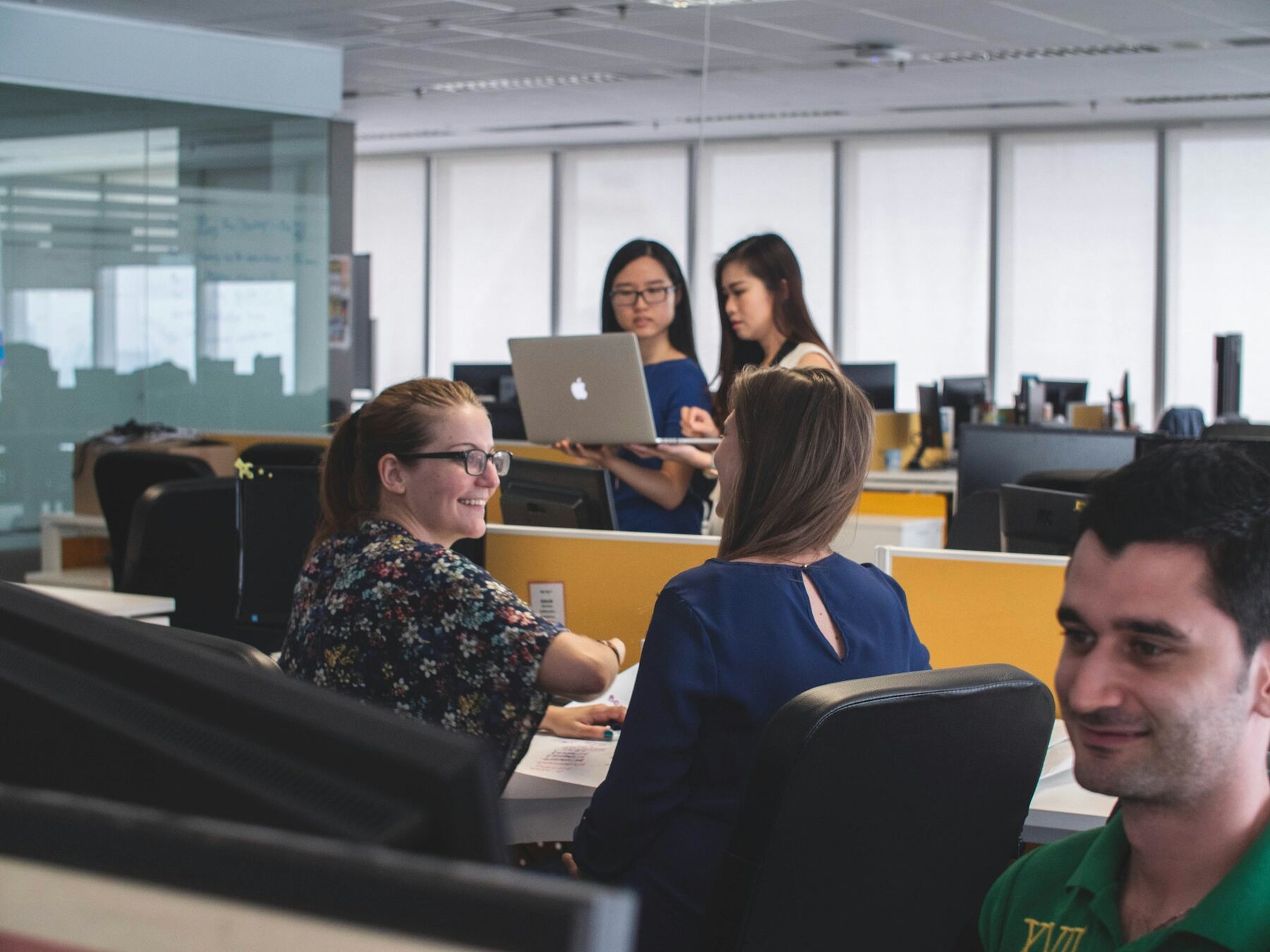 A group of people sitting at desks working on laptops