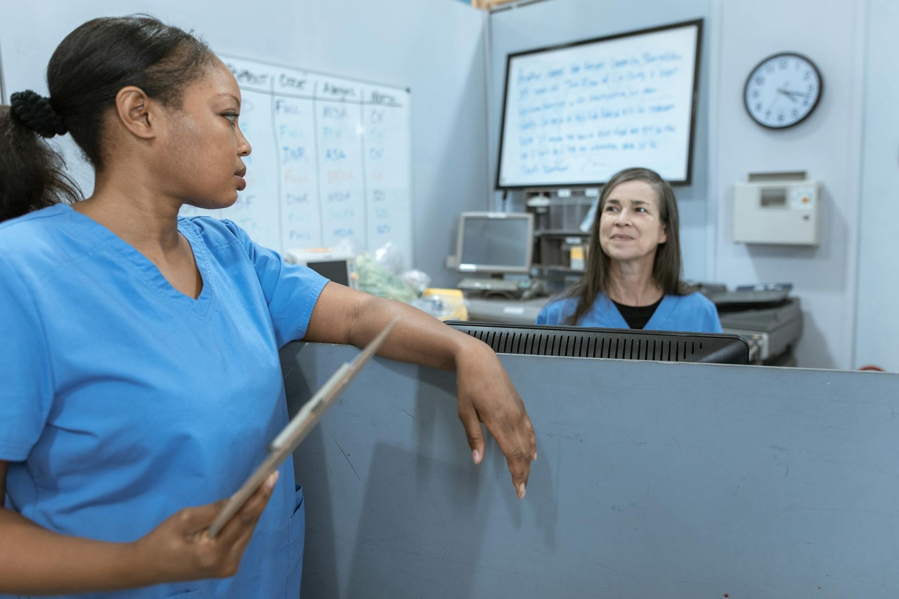 Two women in blue scrub suits engaged in conversation