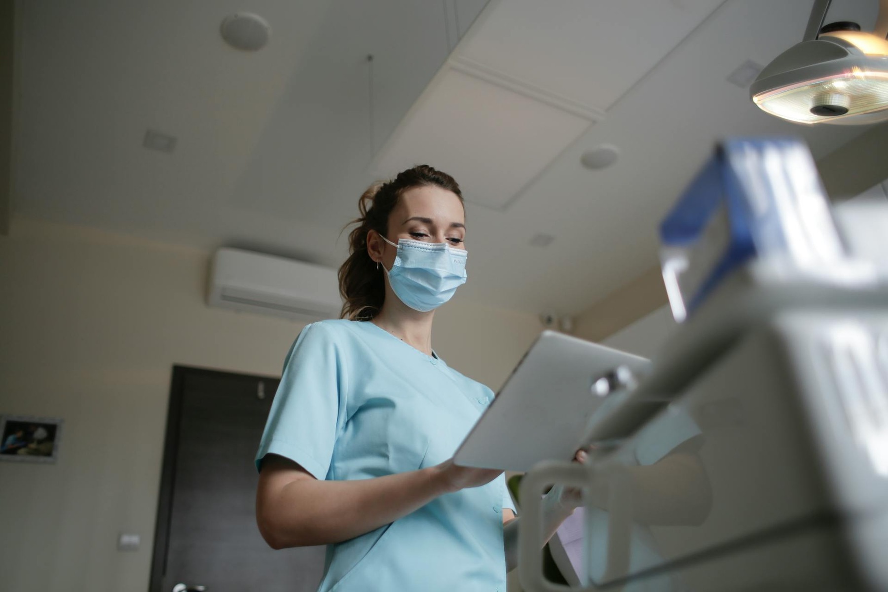 A nurse wearing a surgical mask holding a tablet