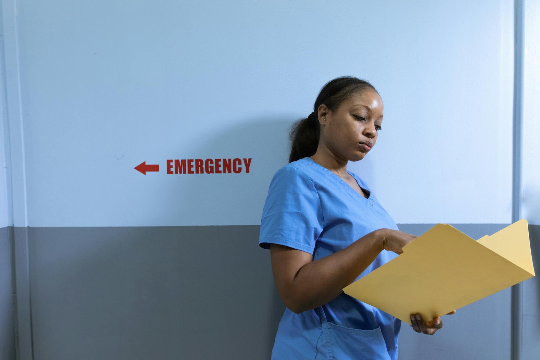 A nurse holding a folder with an emergency sign