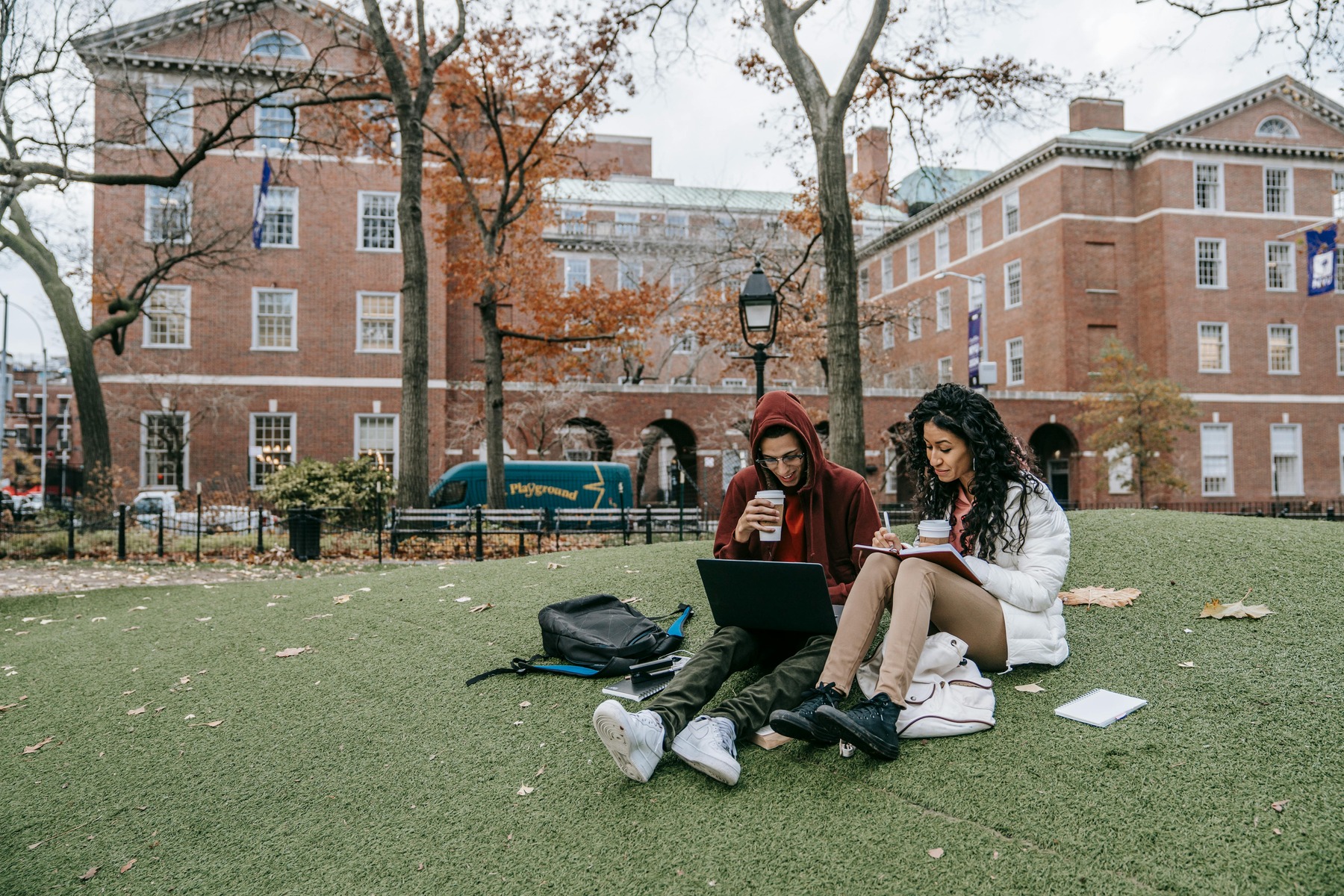 Two students sitting on the campus lawn while studying
