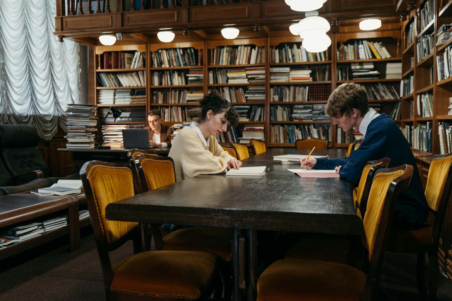 Two individuals studying together at a library table