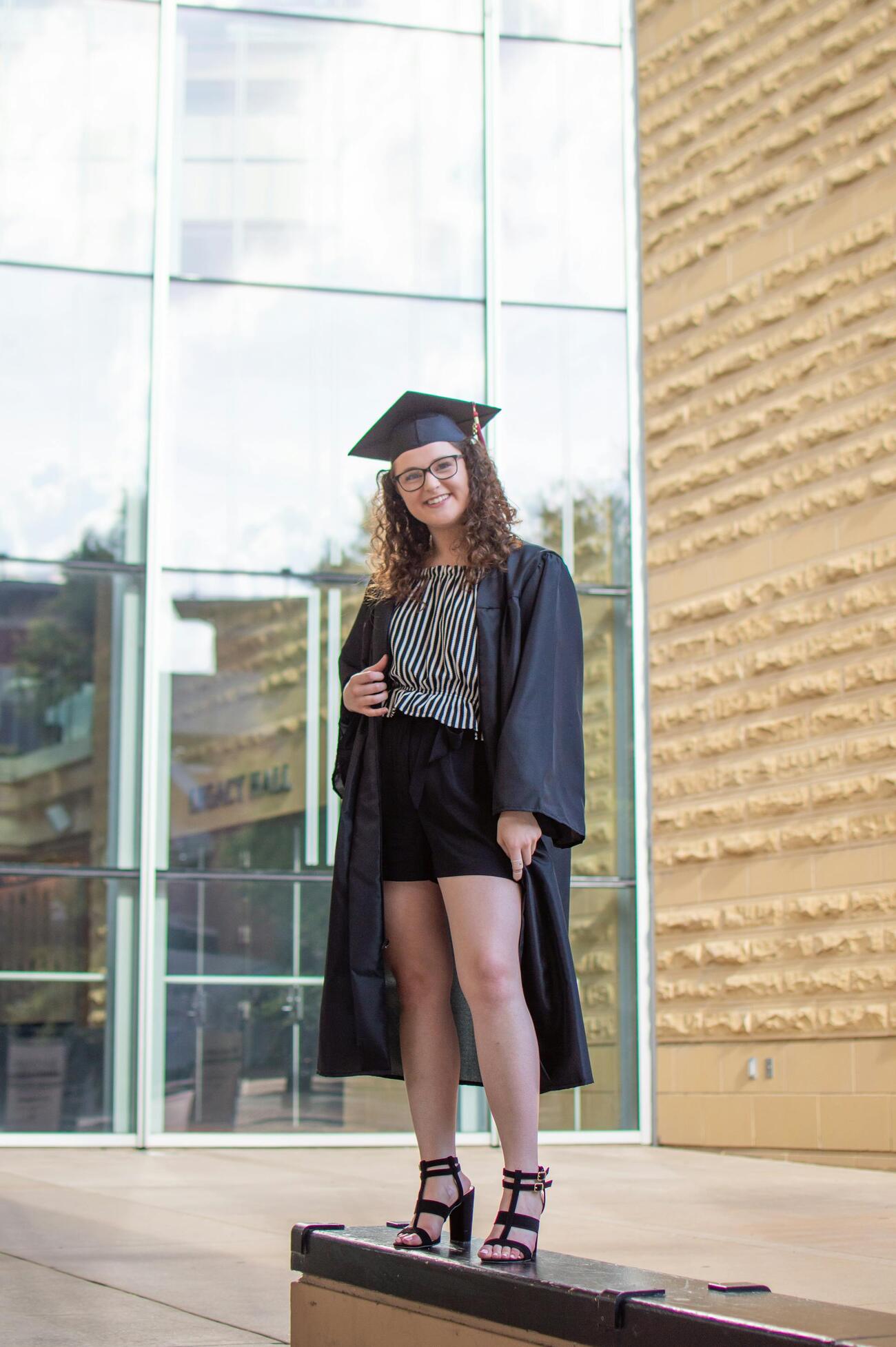 A woman in a graduation gown standing on a ledge