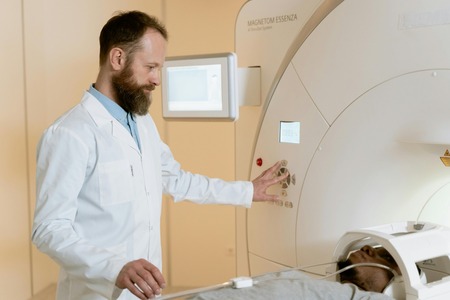 Man assisting a patient as he goes in a CT scan