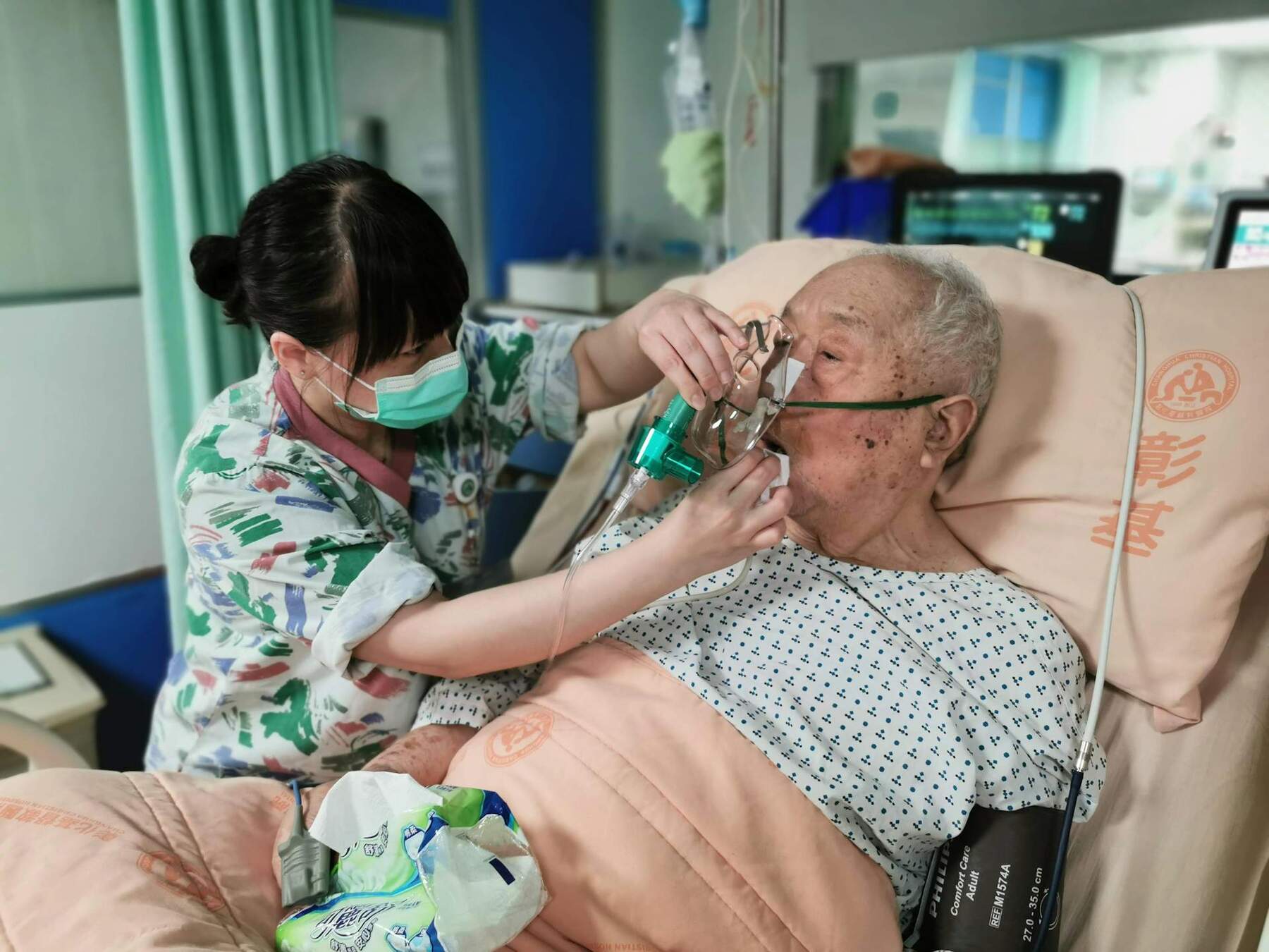 An elderly man receiving oxygen from a nurse in a medical facility