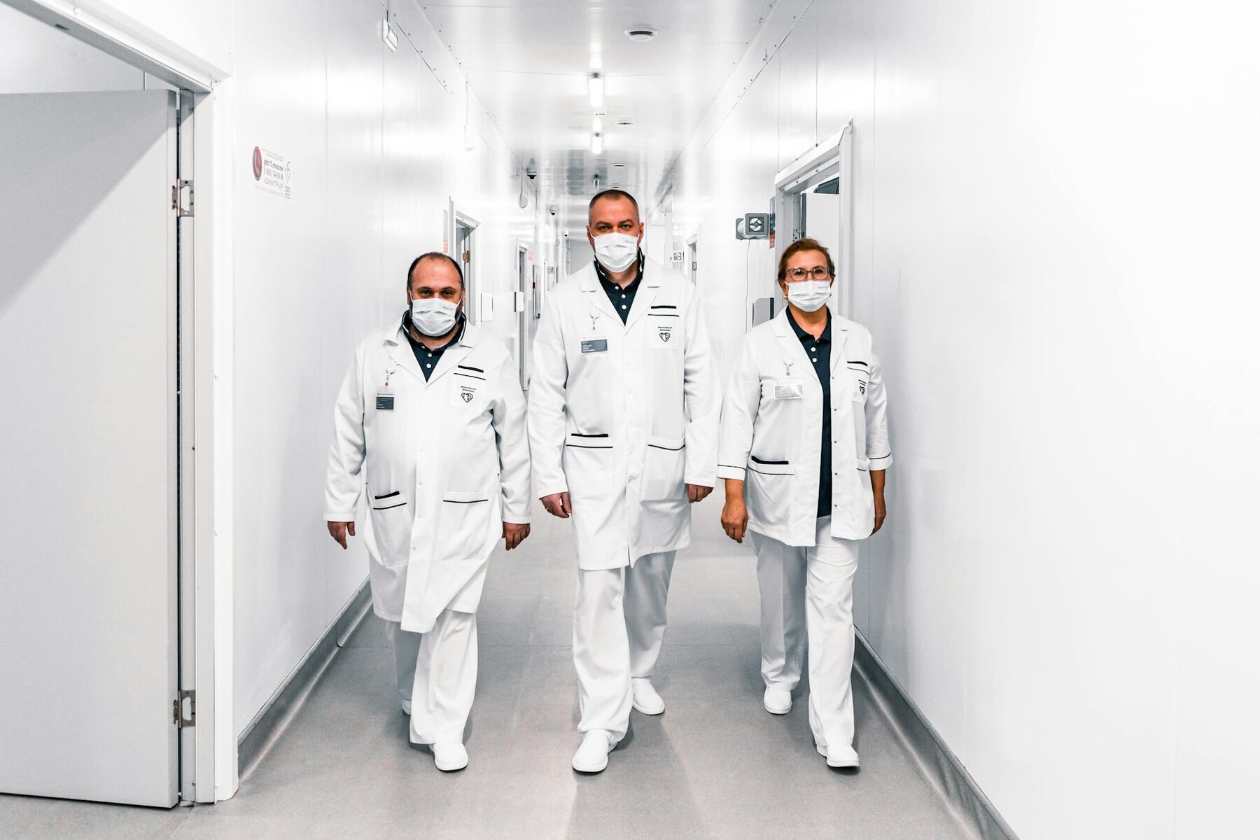 Three doctors in white coats walking down a hospital hallway