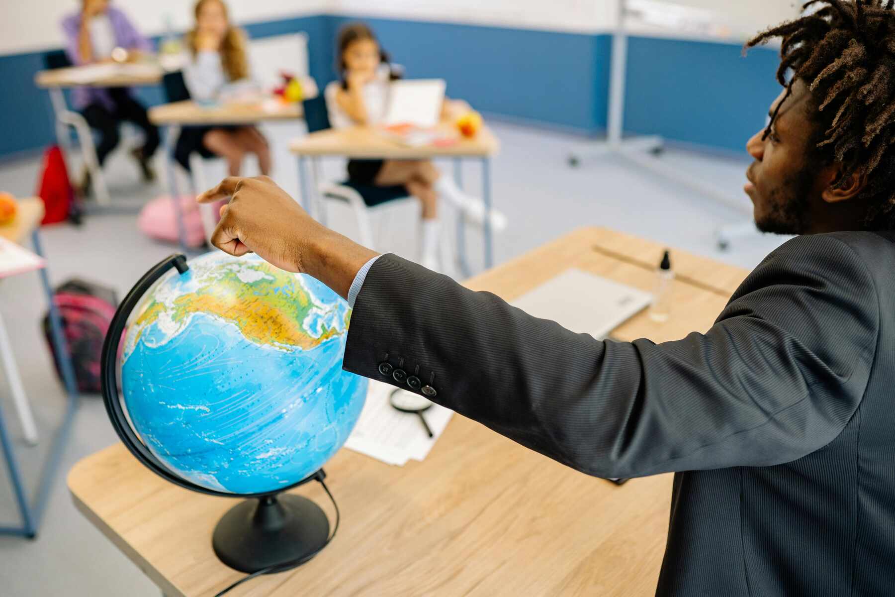 A teacher in front while showing a globe to her students