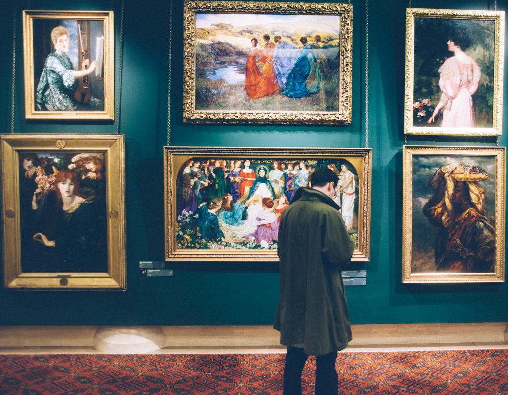 A man standing in front of the paintings on a museum